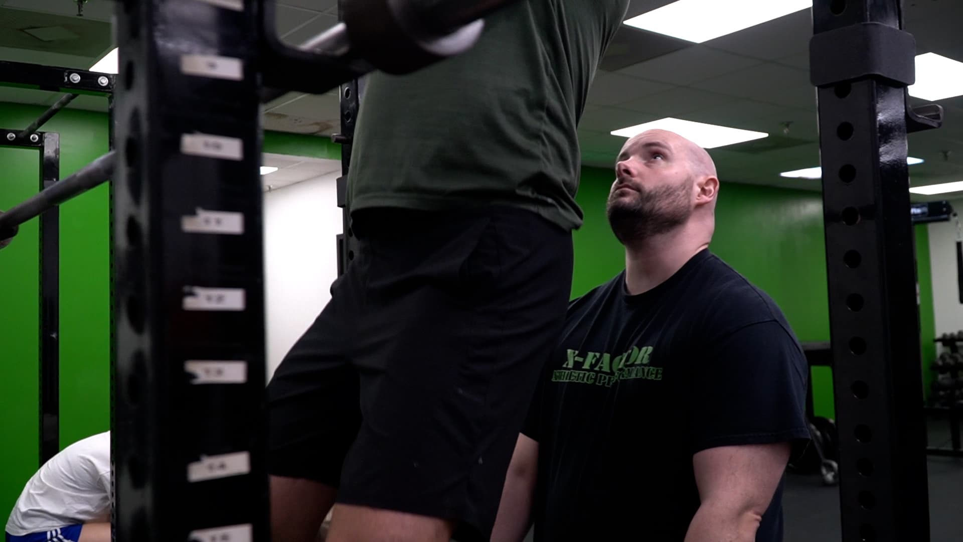 Coach Brett Woldanski spotting an athlete at X Factor Athletic Performance — strength and conditioning gym in Richmond VA